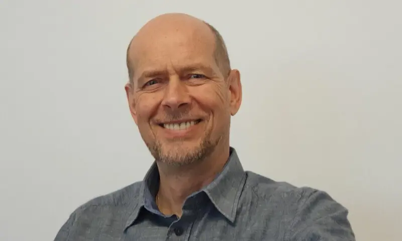 Dirk Kruse - Heilpraktiker für Psychotherapie und Coach - im grauen Hemd vor hellem Hintergrund, Halbporträt mit Blick in die Kamera.